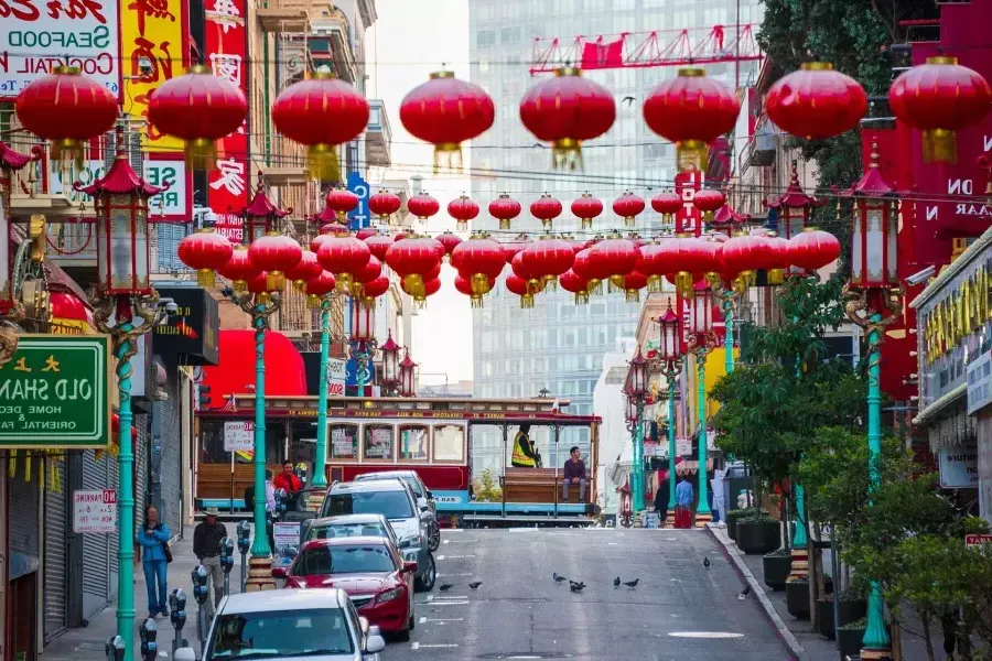 Abgebildet ist eine hügelige Straße in 贝博体彩apps Chinatown mit baumelnden roten Laternen und einer vorbeifahrenden Straßenbahn.